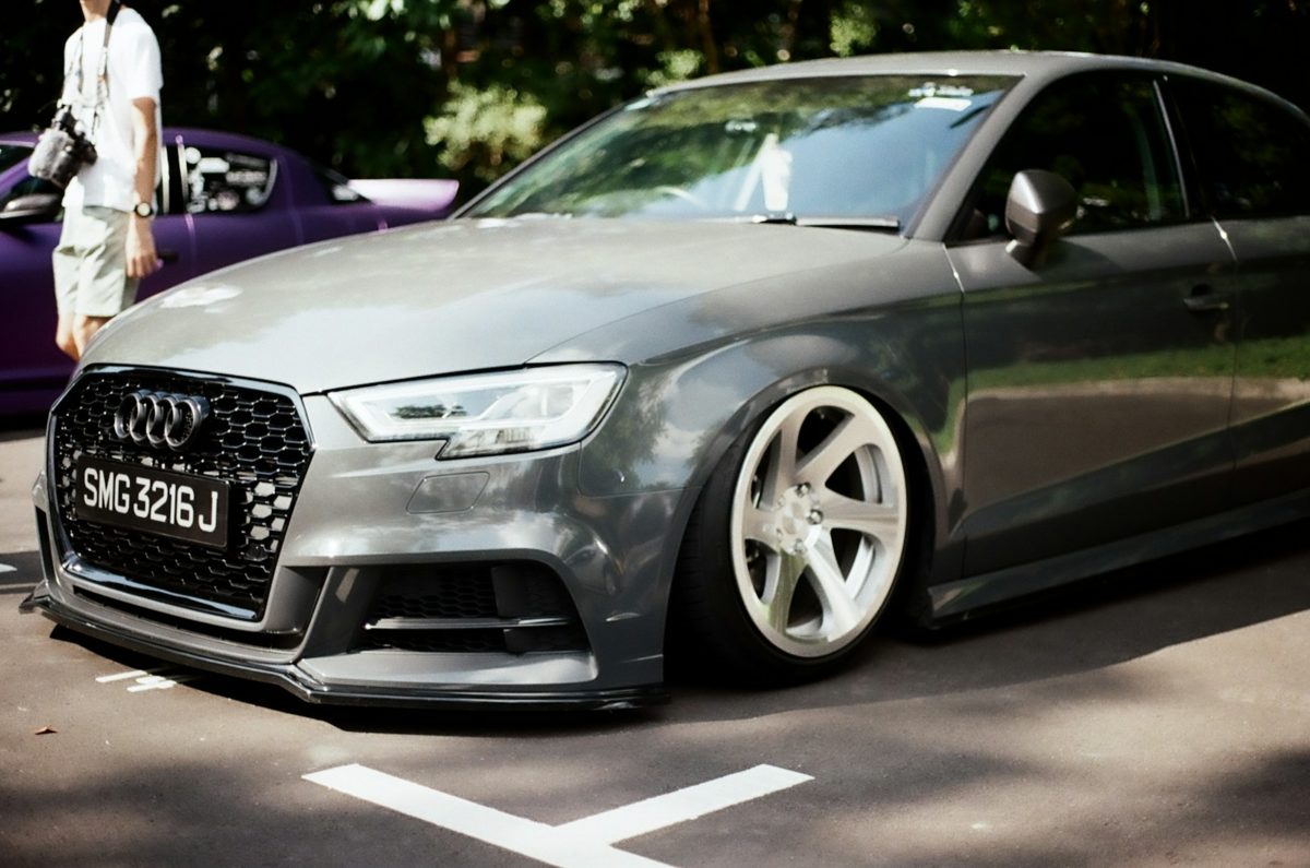 a grey car parked in a parking lot next to a purple car